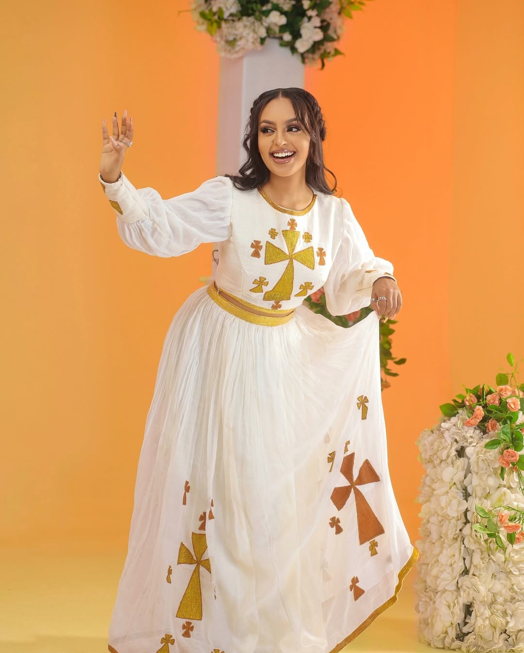 Woman in a white dress with gold and brown patterns against an orange background Golden Ethiopian Habesha Dress Handcrafted Zuria Kemis Set ethgebya gebeya usa zuria habesha kemis