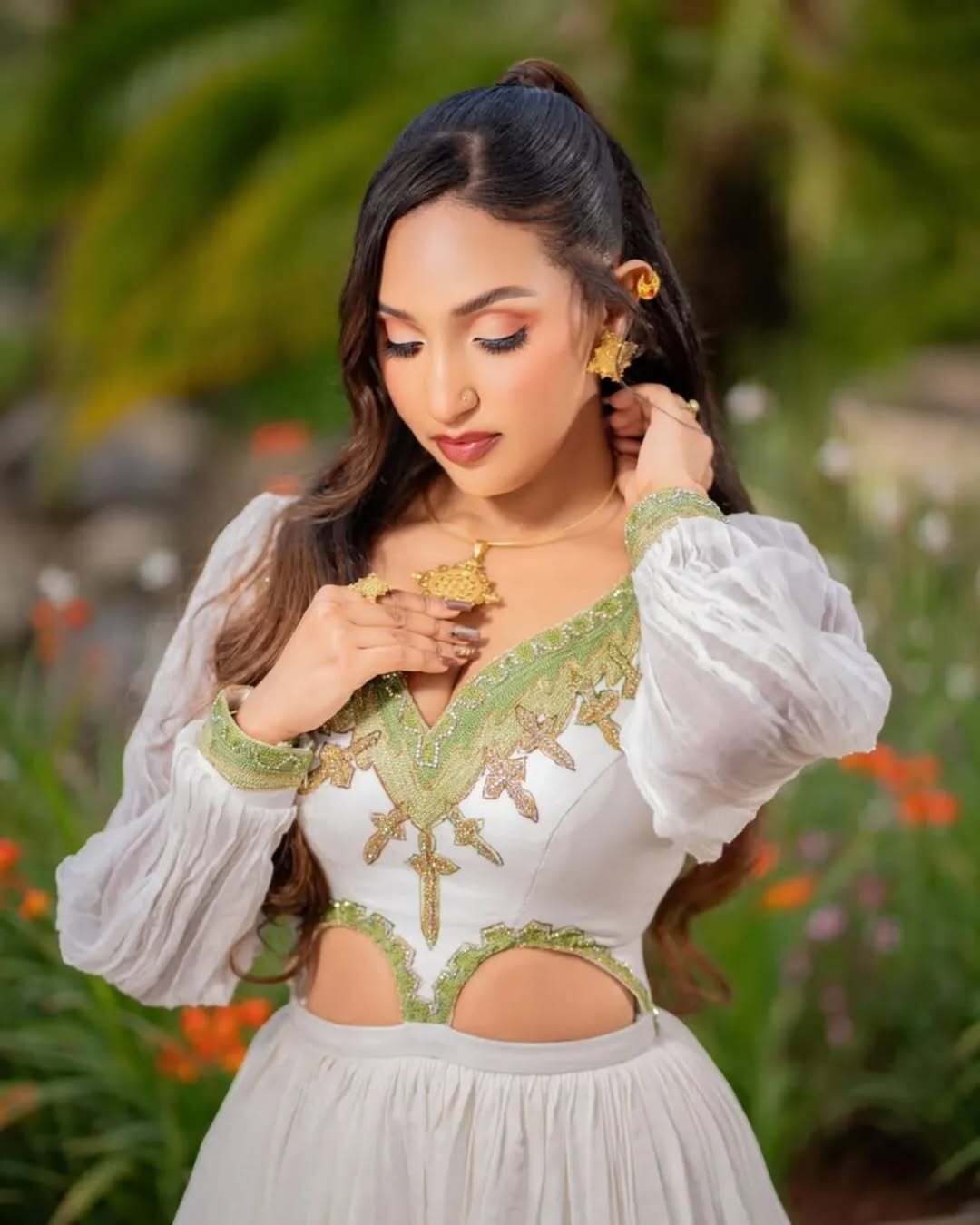 Woman in a white and green embroidered dress standing in a garden. Grass Green Modern Zuria Kemis Elegant Ethiopian Traditional Dress Ethgebya