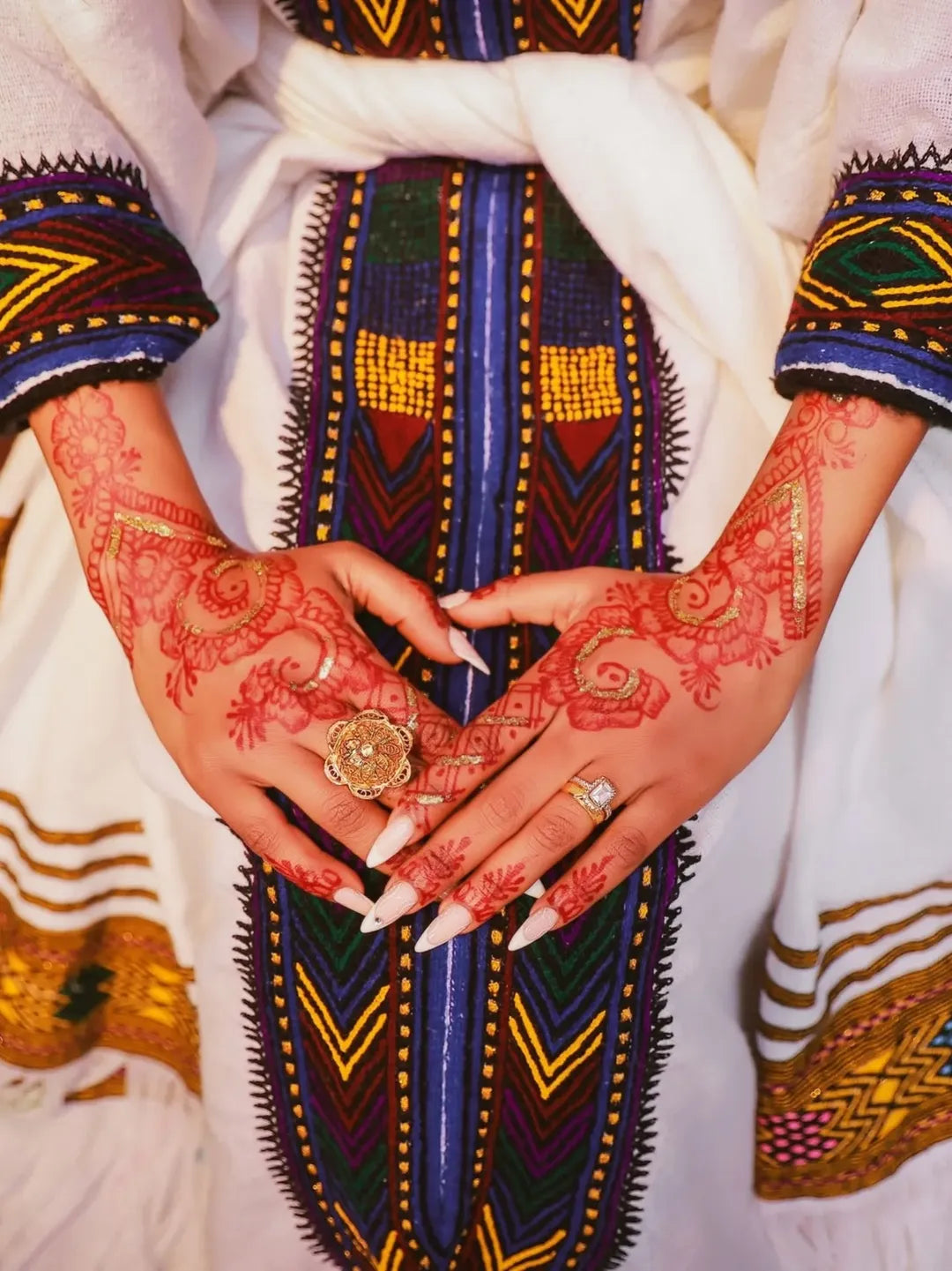 Close-up of hands with red henna designs, wearing rings, against a colorful traditional garment. New Ethiopian & Eritrean Axum Habesha Dress Handwoven Tilet Kemis Ethiopia Gebeya Ethgebya