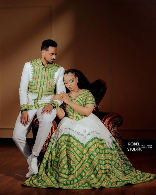 Couple in traditional green and white attire sitting on a brown couch. ethiopian and eritrean ethgebya