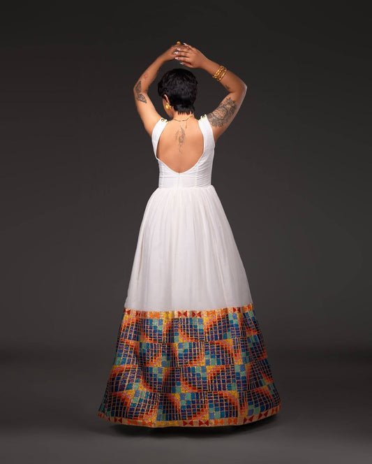 Person wearing a white dress with a colorful patterned bottom half on a dark background Open-Back Modern Zuria Habesha Kemis Elegant Ethiopian Dress ethgebya gebeya usa habesha kemis
