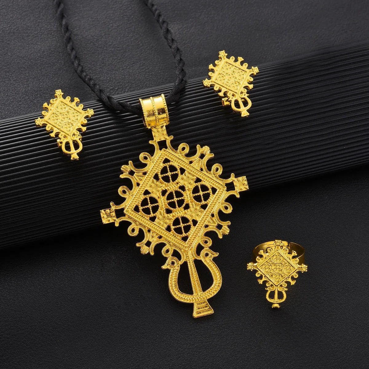 Gold jewelry set with pendant, earrings, and ring on a black background