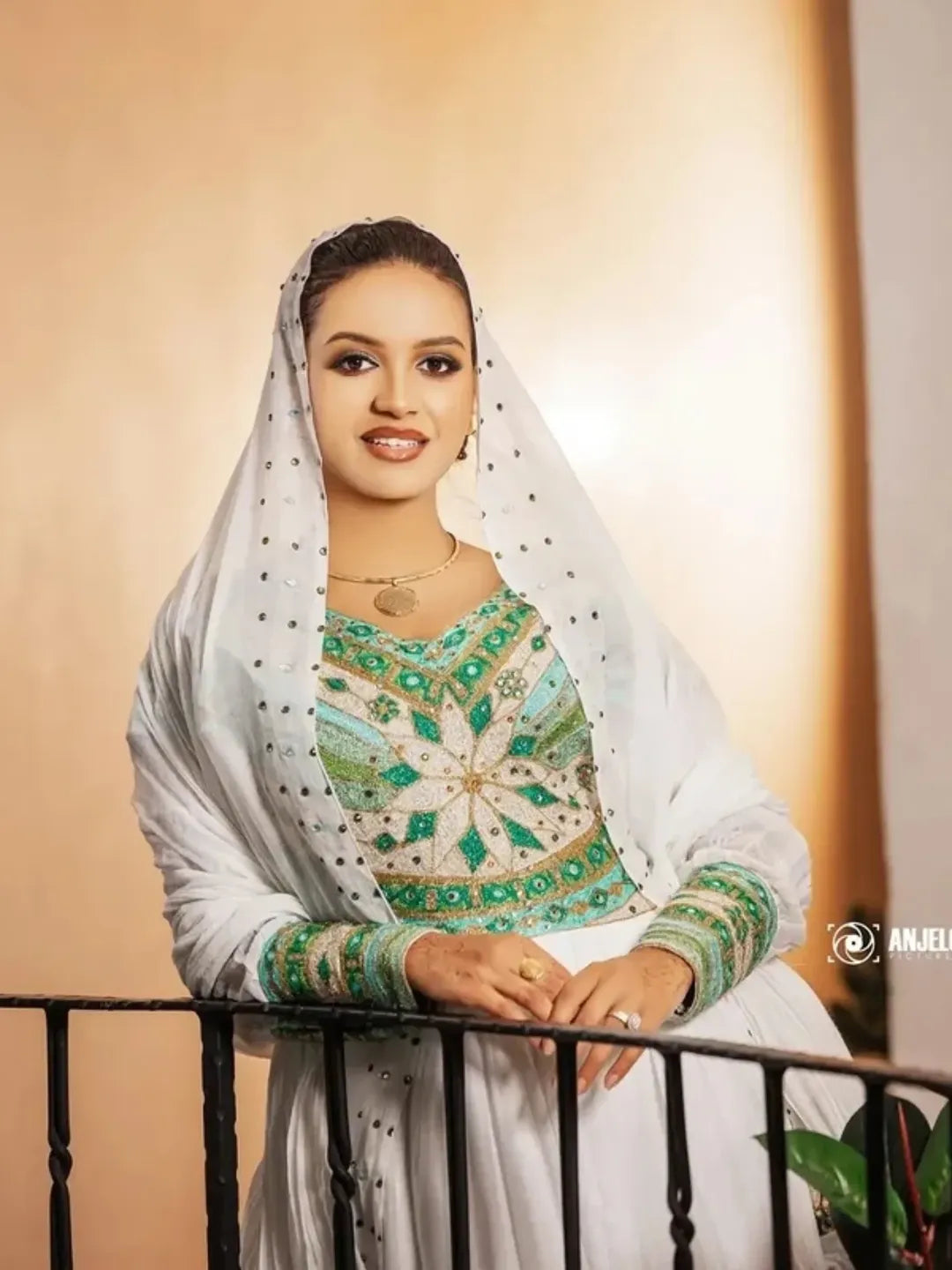 Woman in traditional attire with a white dupatta and green embroidered top, sitting on a balcony. Luxury Green Habesha Couple Outfit Matching Ethiopian Attire Set ethgebya gebeya usa habesha couples