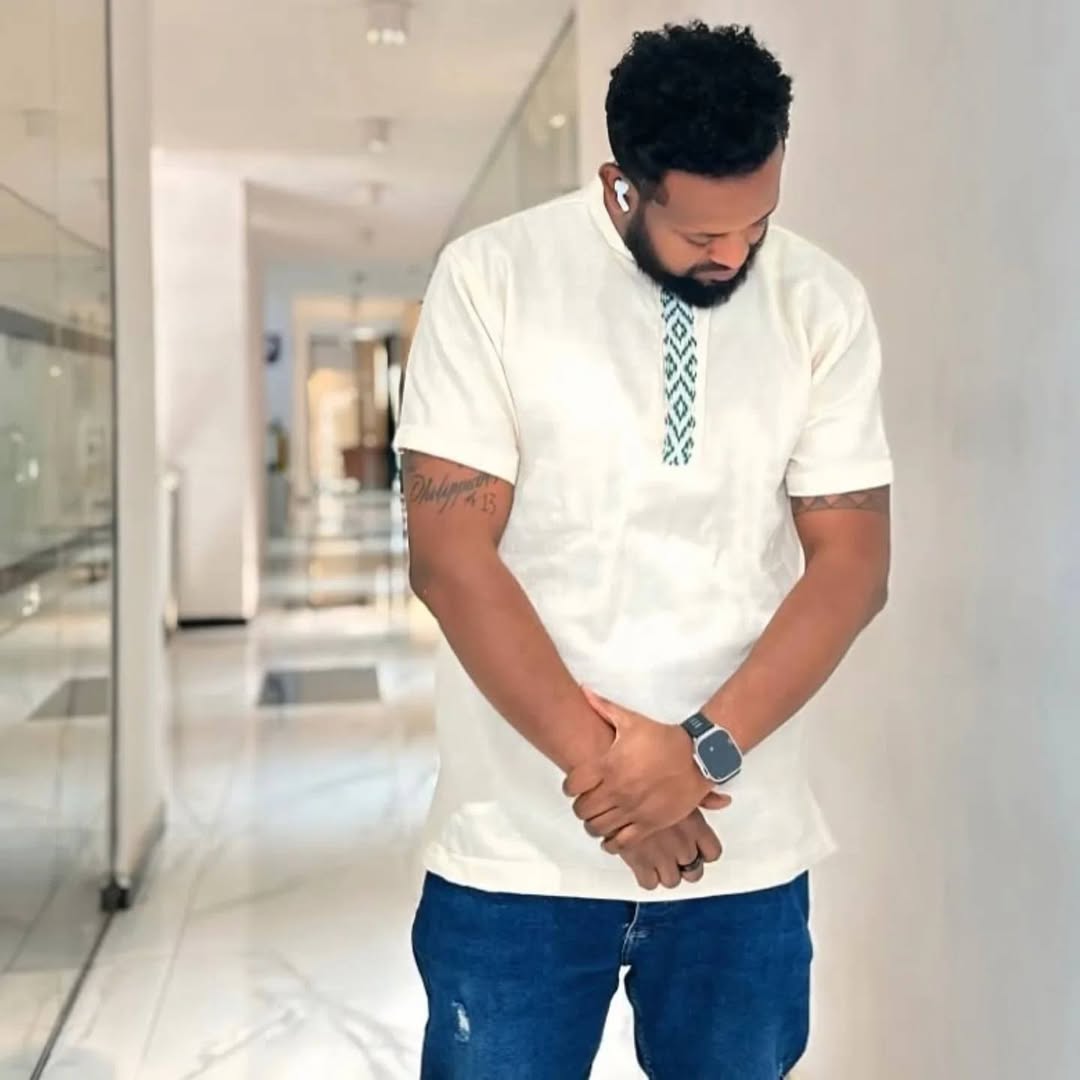 Man wearing a white shirt with a patterned design and blue jeans indoors. Traditional Green Accent Habesha Men’s Cloth Ethiopian Eritrean Attire Ethiopia gebeya