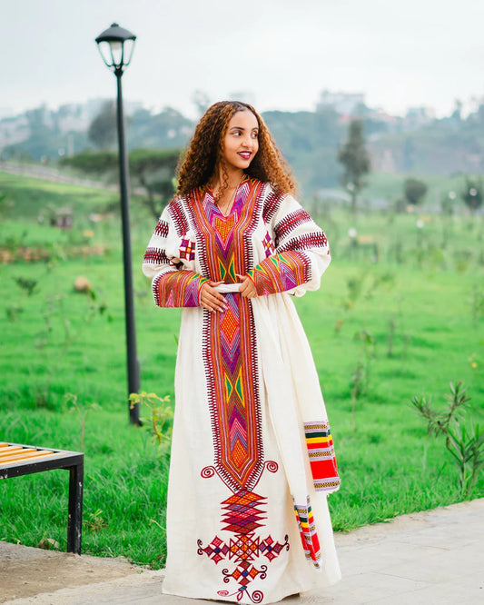 Woman wearing a colorful traditional dress in a park setting gondar habesha kemis ethgebya