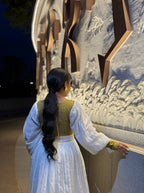 Woman in a white dress with a green top standing in front of a decorative wall. Gold Zuria Habesha Kemis New Elegant Modern Ethiopian Dress ethgebya gebeya habesha kemis