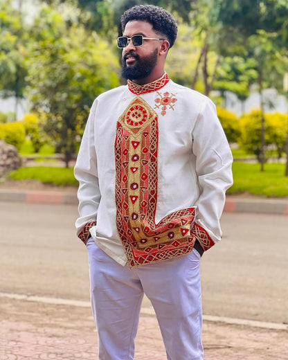 Man wearing a traditional embroidered shirt with a park in the background Traditional Habesha Men’s Clothing | New Ethiopian & Eritrean Attire Ethgebya