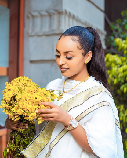 Woman in a white saree holding yellow flowers outdoors Simple Short Golden Habesha Dress Modern Summer Ethiopian Attire ethgebya gebeya usa habesha kemis
