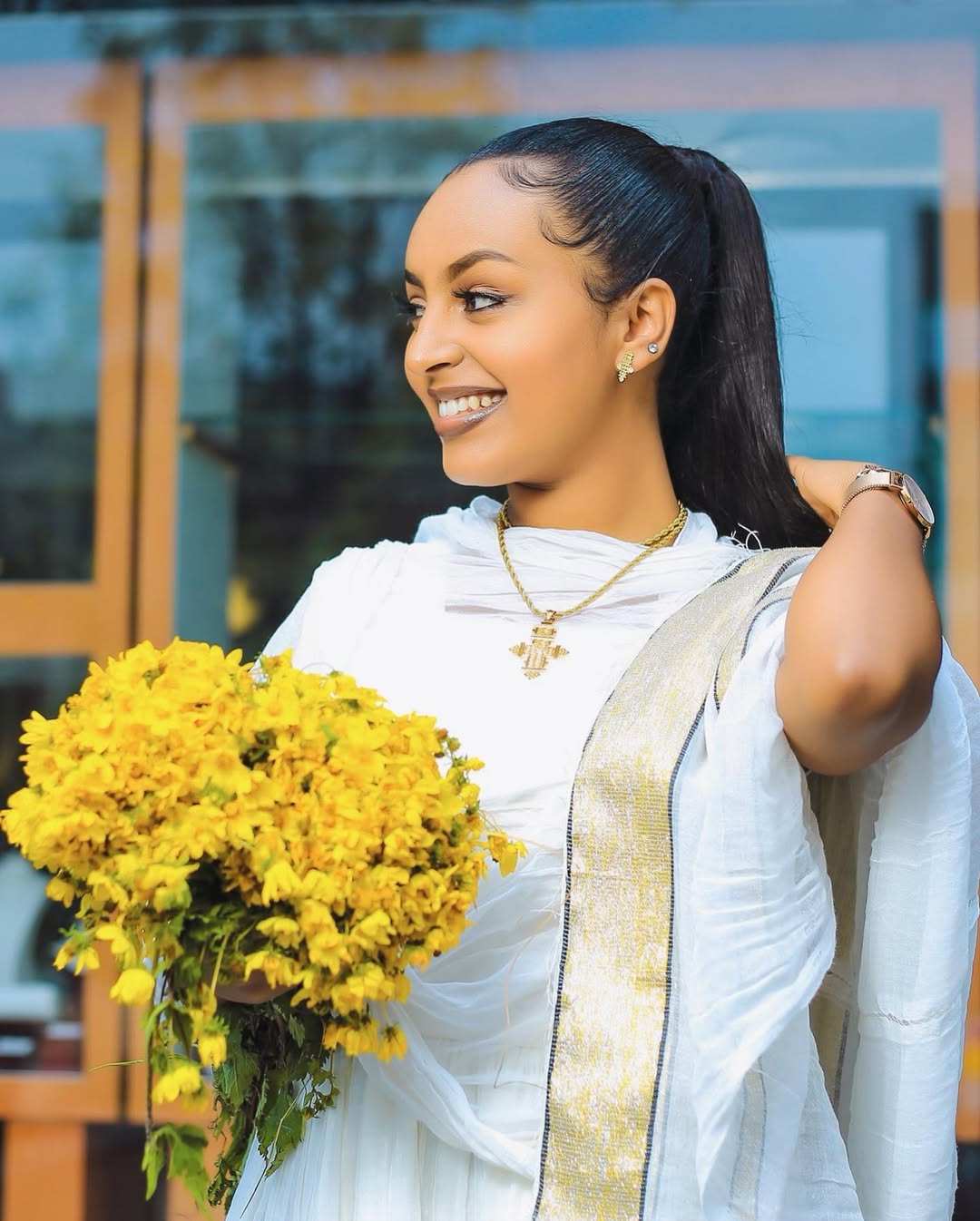 Woman in a white saree holding yellow flowers outdoors Simple Short Golden Habesha Dress Modern Summer Ethiopian Attire ethgebya gebeya usa habesha kemis