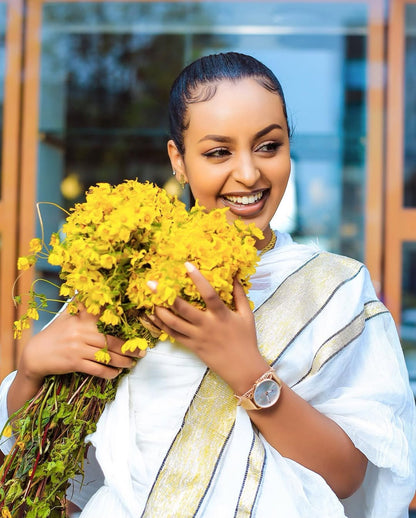 Woman holding a bouquet of yellow flowers outdoors Simple Short Golden Habesha Dress Modern Summer Ethiopian Attire ethgebya gebeya usa habesha kemis