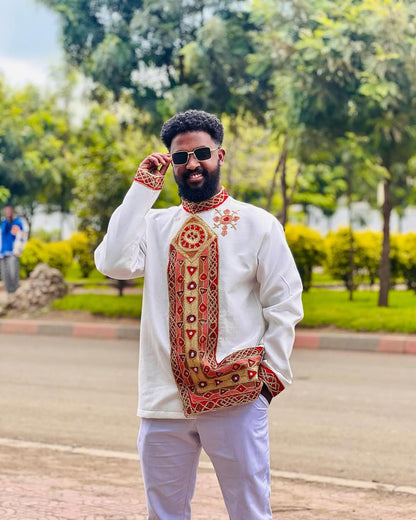 Man wearing a traditional outfit with intricate patterns outdoors Traditional Habesha Men’s Clothing | New Ethiopian & Eritrean Attire Ethgebya