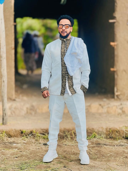 Man in formal attire standing outdoors with a rustic background Gold Habesha Men’s Shirt Modern Ethiopian Traditional Wear ethgebya gebeya