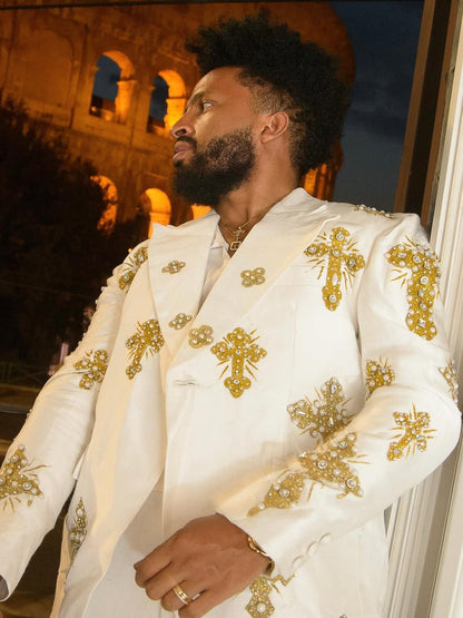 Man wearing a white embroidered suit with gold details in an outdoor setting. Gold Tilf Habesha Men’s Shirt Modern Ethiopian Traditional Wear ethgebya gebeya