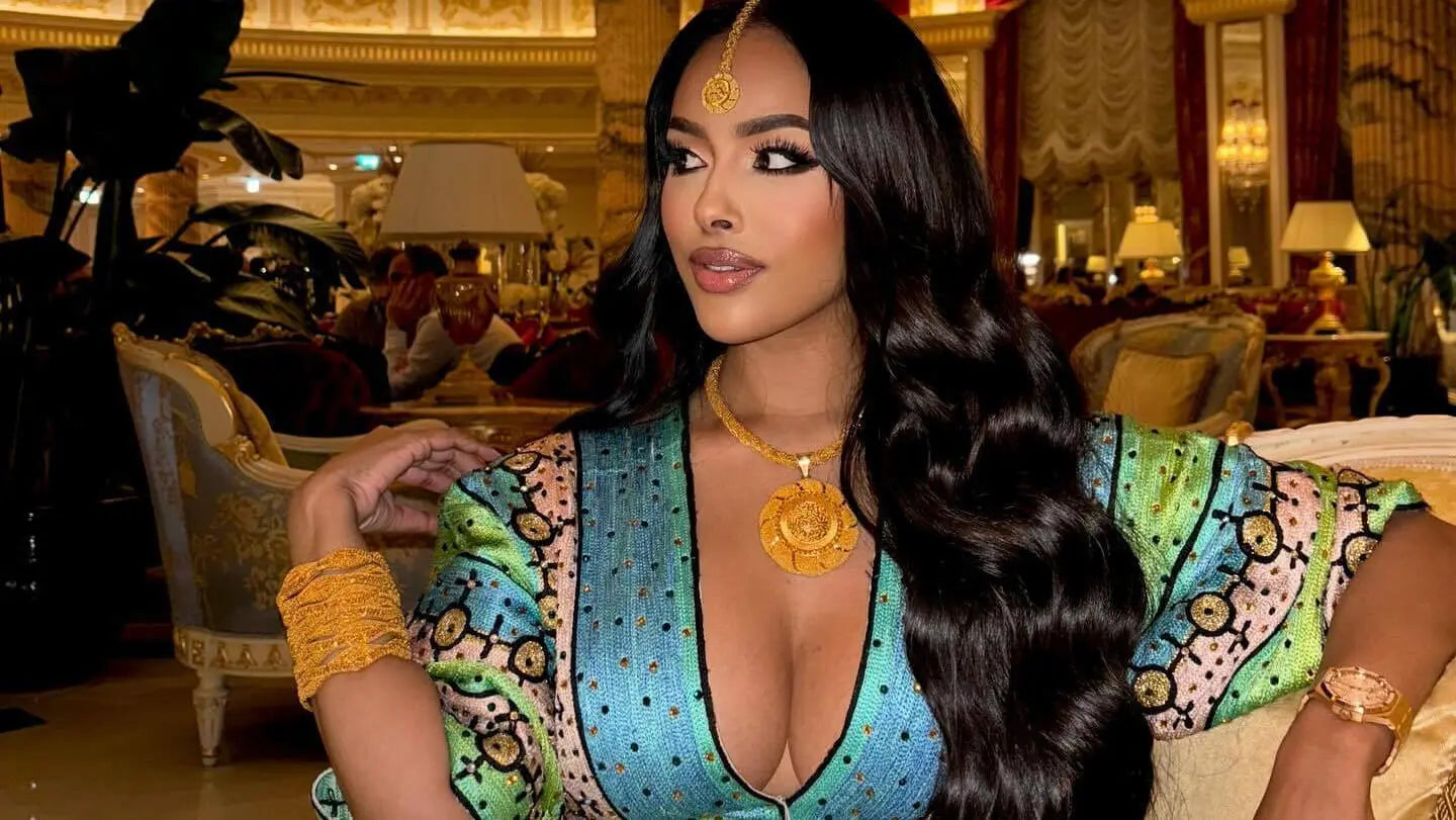 Woman in a colorful traditional outfit with gold jewelry in an elegant interior setting