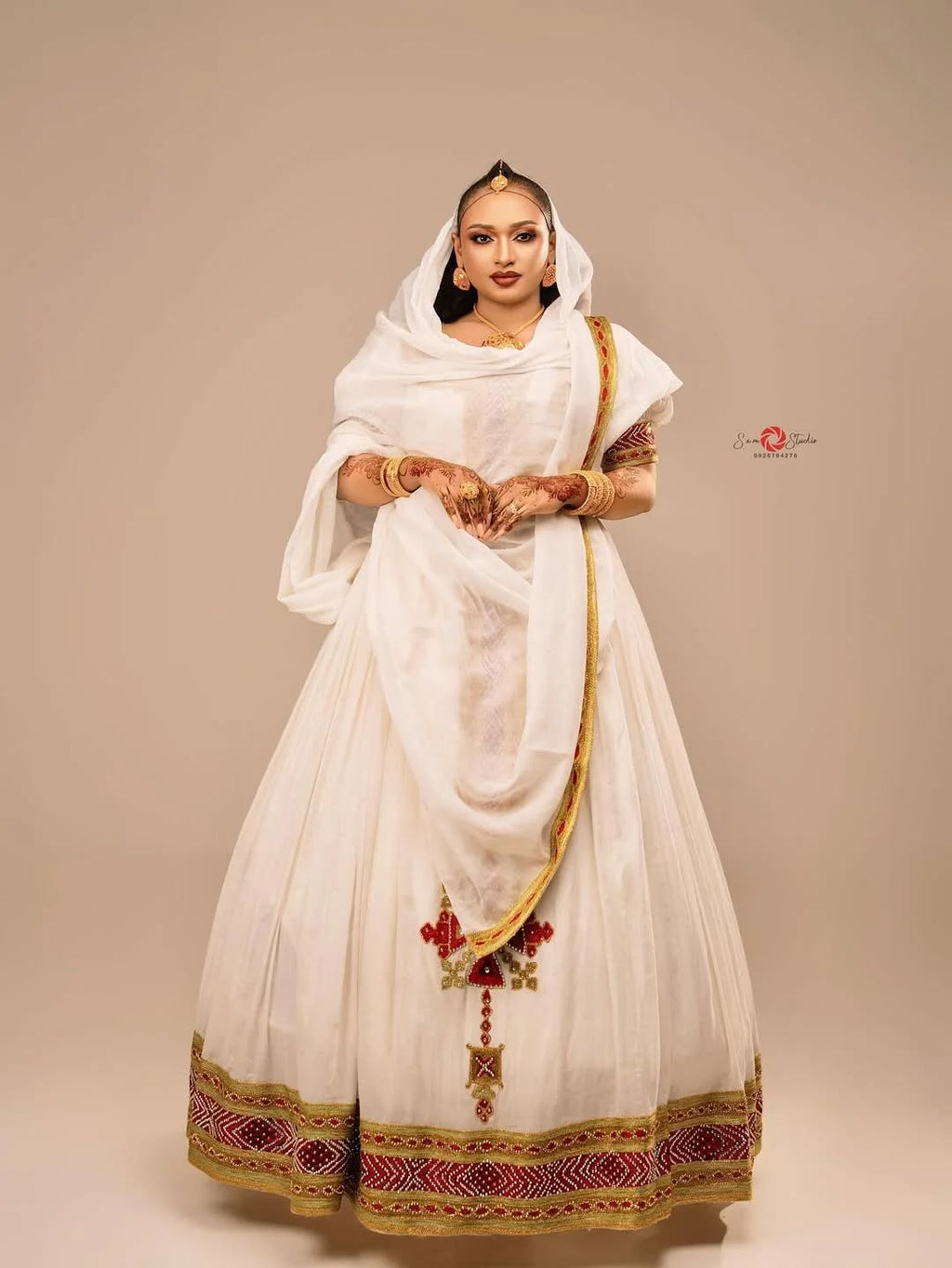 Woman wearing a traditional white outfit with gold and red details on a beige background