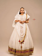 Woman wearing a traditional white outfit with gold and red details on a beige background