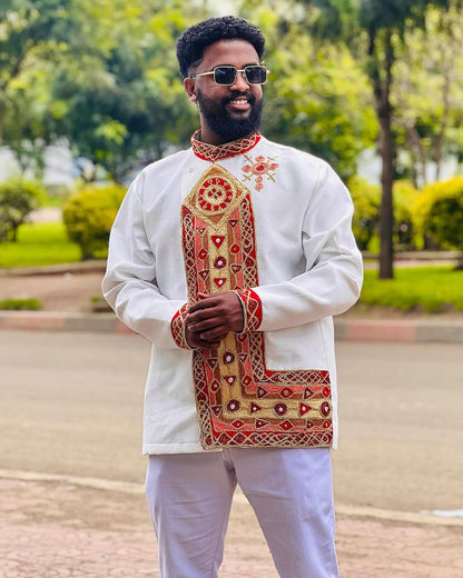 Man wearing a traditional embroidered outfit with sunglasses outdoors. Traditional Habesha Men’s Clothing | New Ethiopian & Eritrean Attire Ethgebya