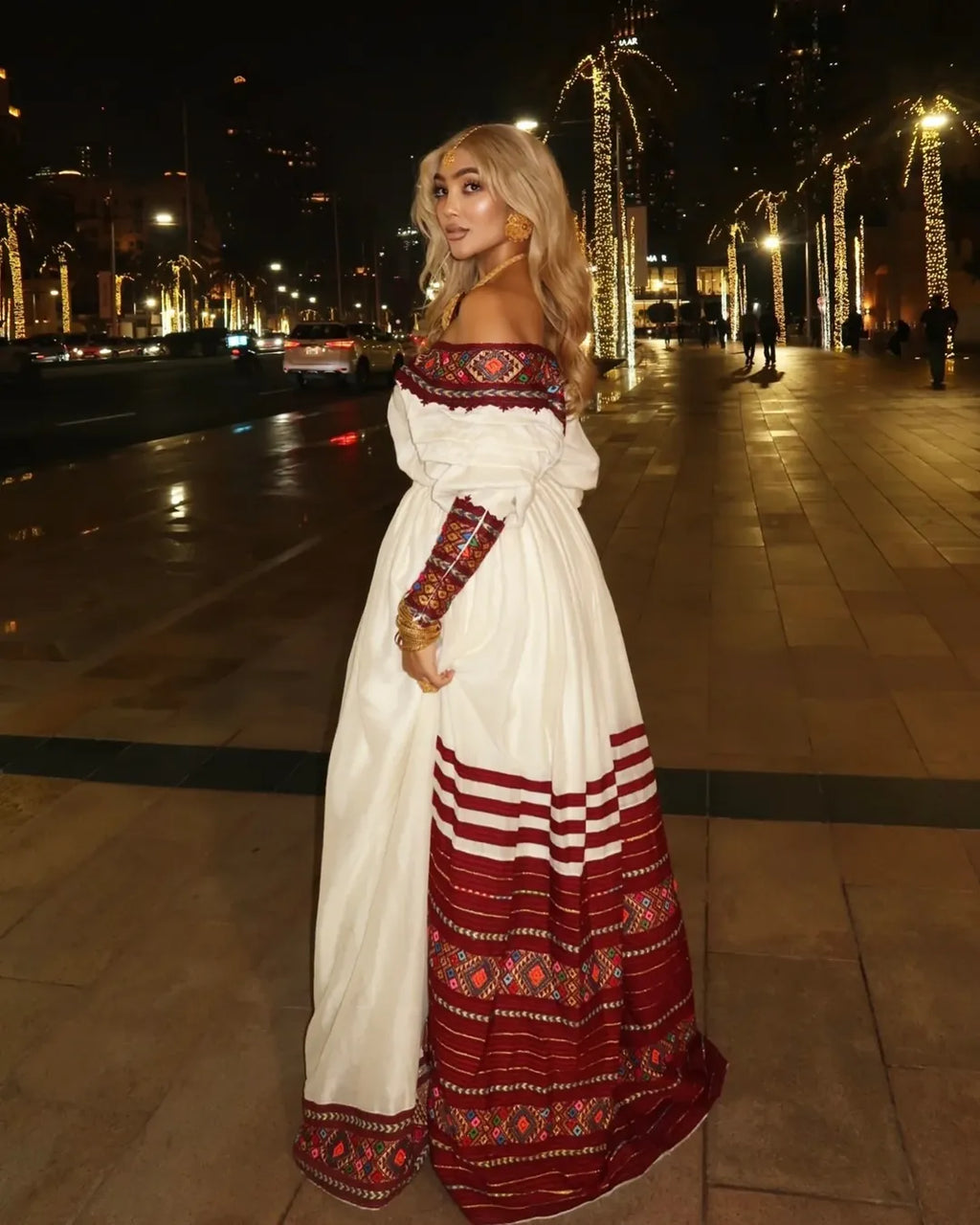 Woman in a white and red traditional outfit standing on a city street at night. Red Zuria Habesha Kemis | Handcrafted Ethiopian & Eritrean Fetil Dress Ethgebya