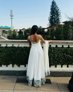Woman in a white traditional outfit with floral patterns standing outdoors.Luxury Navy, Gold & Green Zuria Kemis