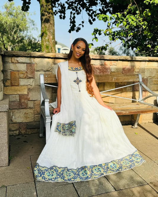 Woman in a white dress with floral patterns sitting outdoors on a stone patio. Luxury Navy, Gold & Green Zuria Kemis