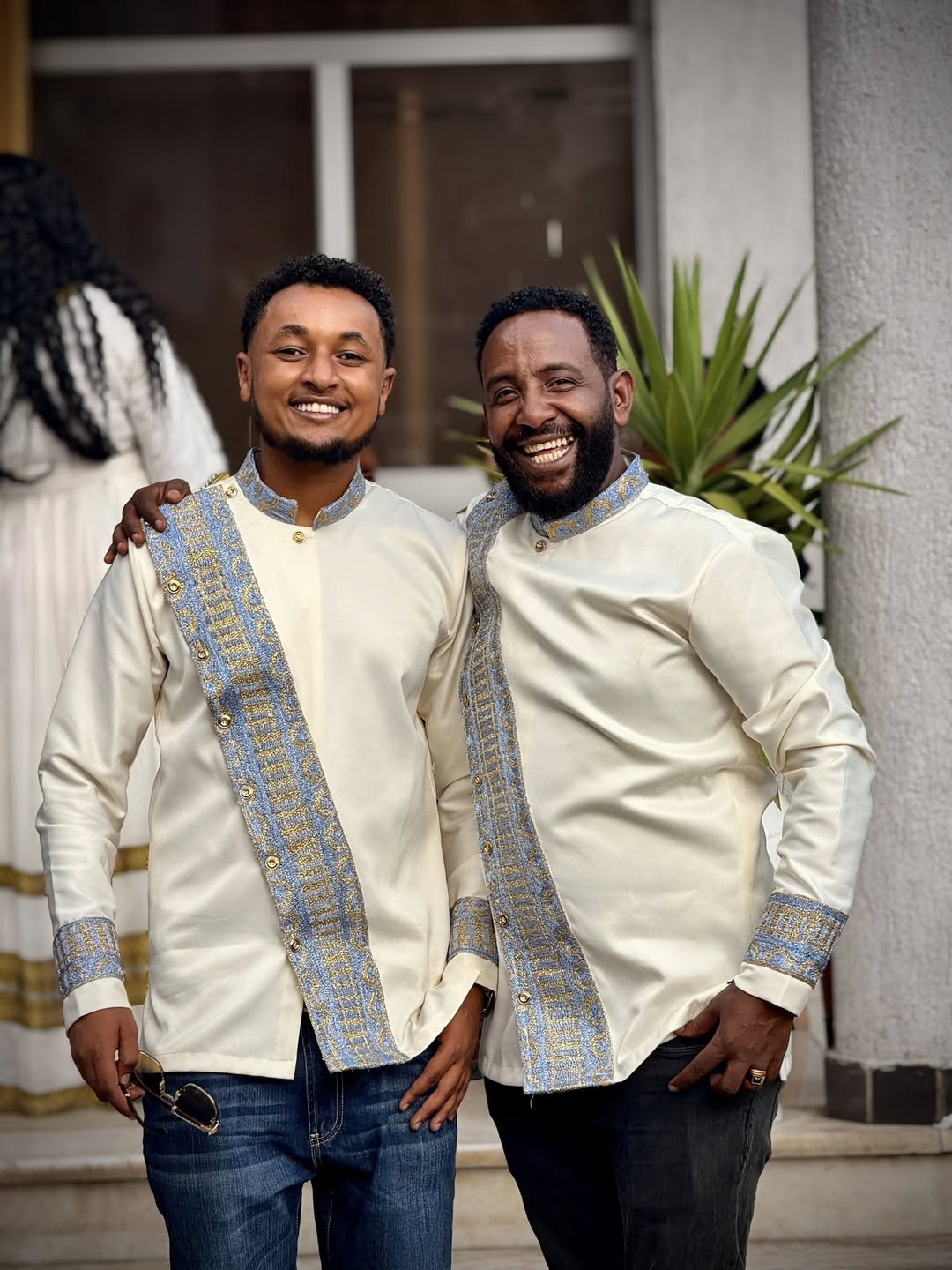 Two men wearing matching traditional outfits standing together outdoors. Modern Habesha Shirt for Men New Ethiopian Cultural Tilet Clothing Ethgebya