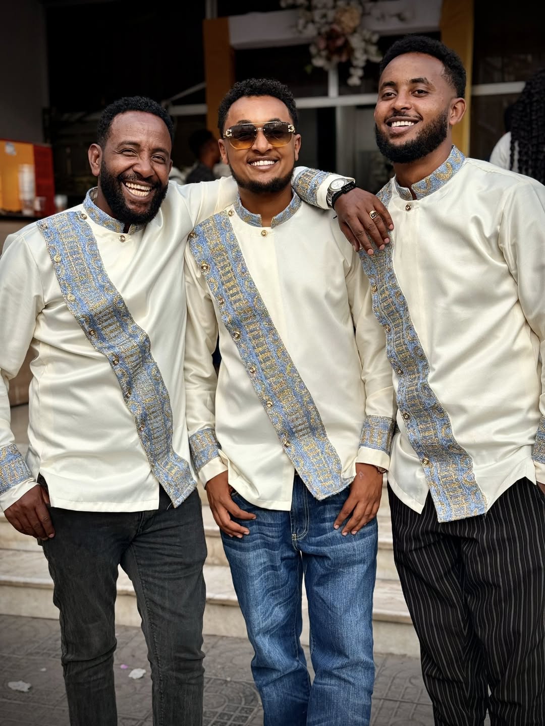 Three men in matching outfits with decorative patterns standing together. Modern Habesha Shirt for Men New Ethiopian Cultural Tilet Clothing Ethgebya