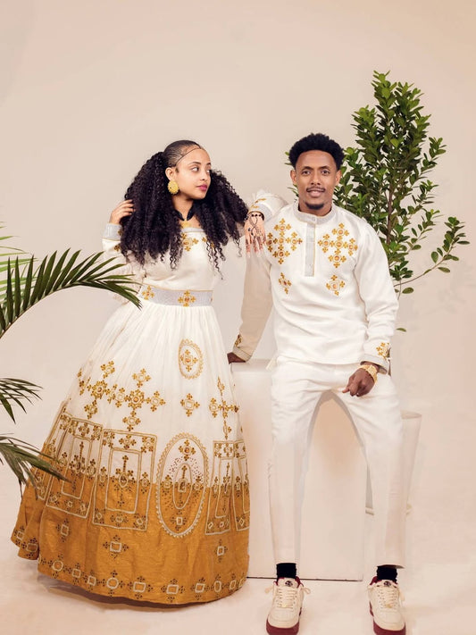 Couple in traditional attire with gold embroidery against a neutral background Ethiopian gown, Habesha wedding dress, Eritrean evening dress, Ethiopian traditional gown, Ethiopian heritage dress, Habesha chic, Eritrean cultural attire, Habesha elegant dress, Eritrean bridal wear, Ethiopian vintage dress, Habesha bridesmaid dress, African ethnic dress, Ethiopian handcrafted dress, Eritrean handcrafted dress, traditional African gown, Habesha festive dress, Ethiopian formal wear,