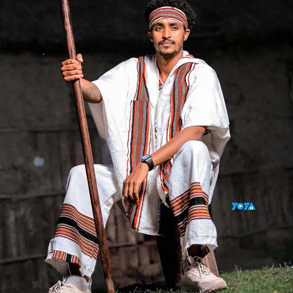 Man in traditional attire holding a spear against a dark background. Oromo Men’s Traditional Clothes Ethiopian Cultural Men's Woya Outfit Ethgebeya