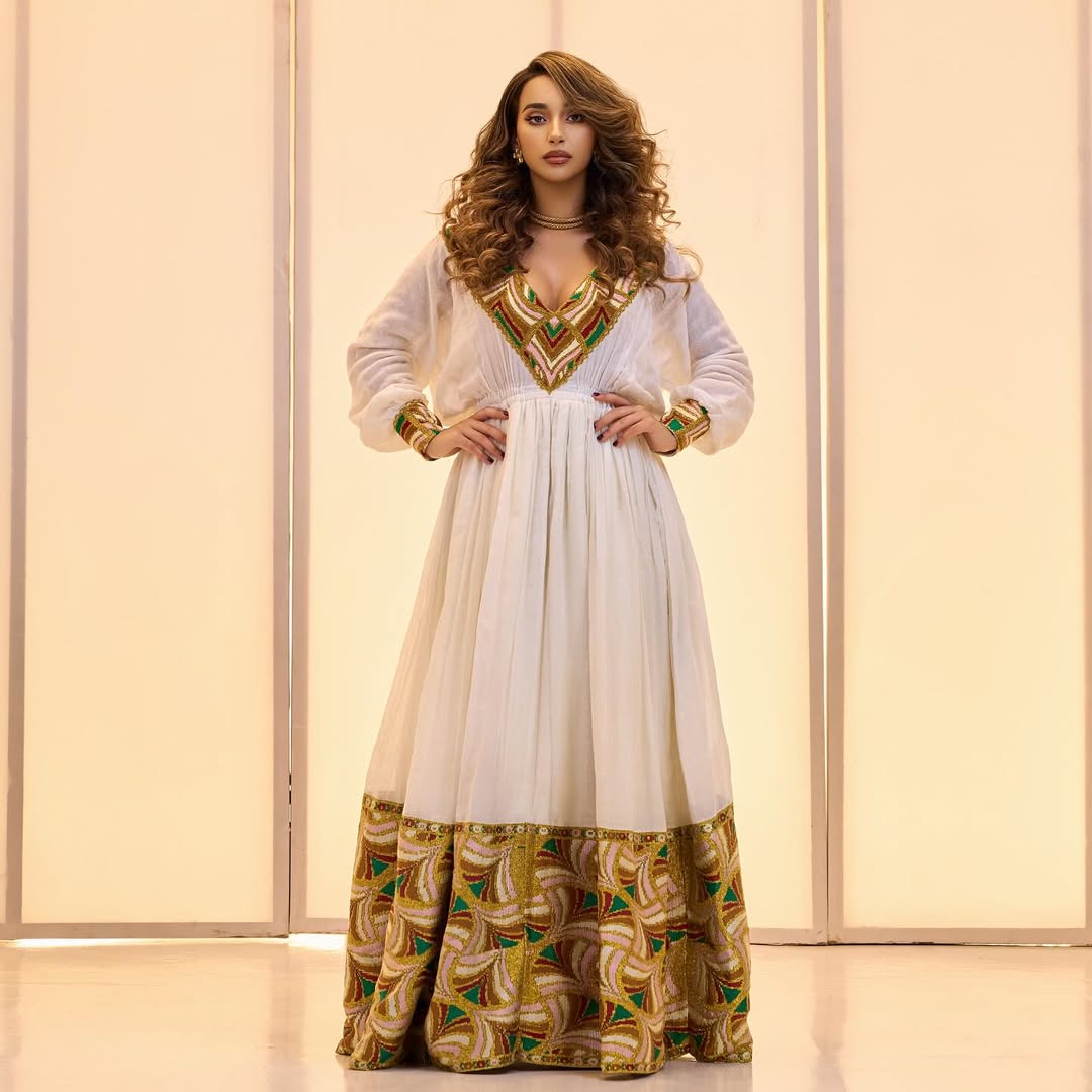 Woman wearing a white dress with gold and green patterns against a light background Golden & Green Modern Zuria Habesha Kemis Ethiopian Traditional Dress ethgebya gebeya
