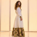 Woman wearing a long, patterned dress with a plain background Golden & Green Modern Zuria Habesha Kemis Ethiopian Traditional Dress ethgebya gebeya