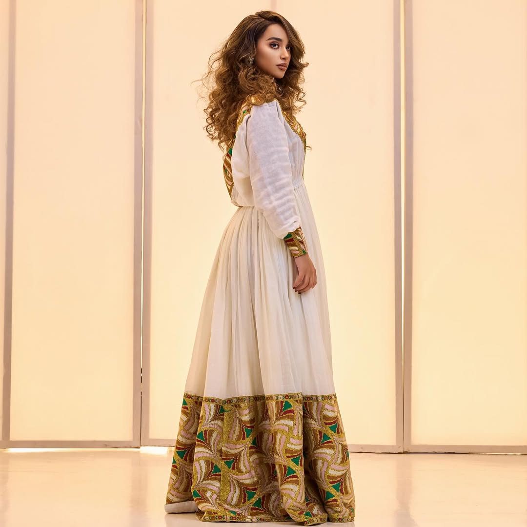Woman wearing a long, patterned dress with a plain background Golden & Green Modern Zuria Habesha Kemis Ethiopian Traditional Dress ethgebya gebeya