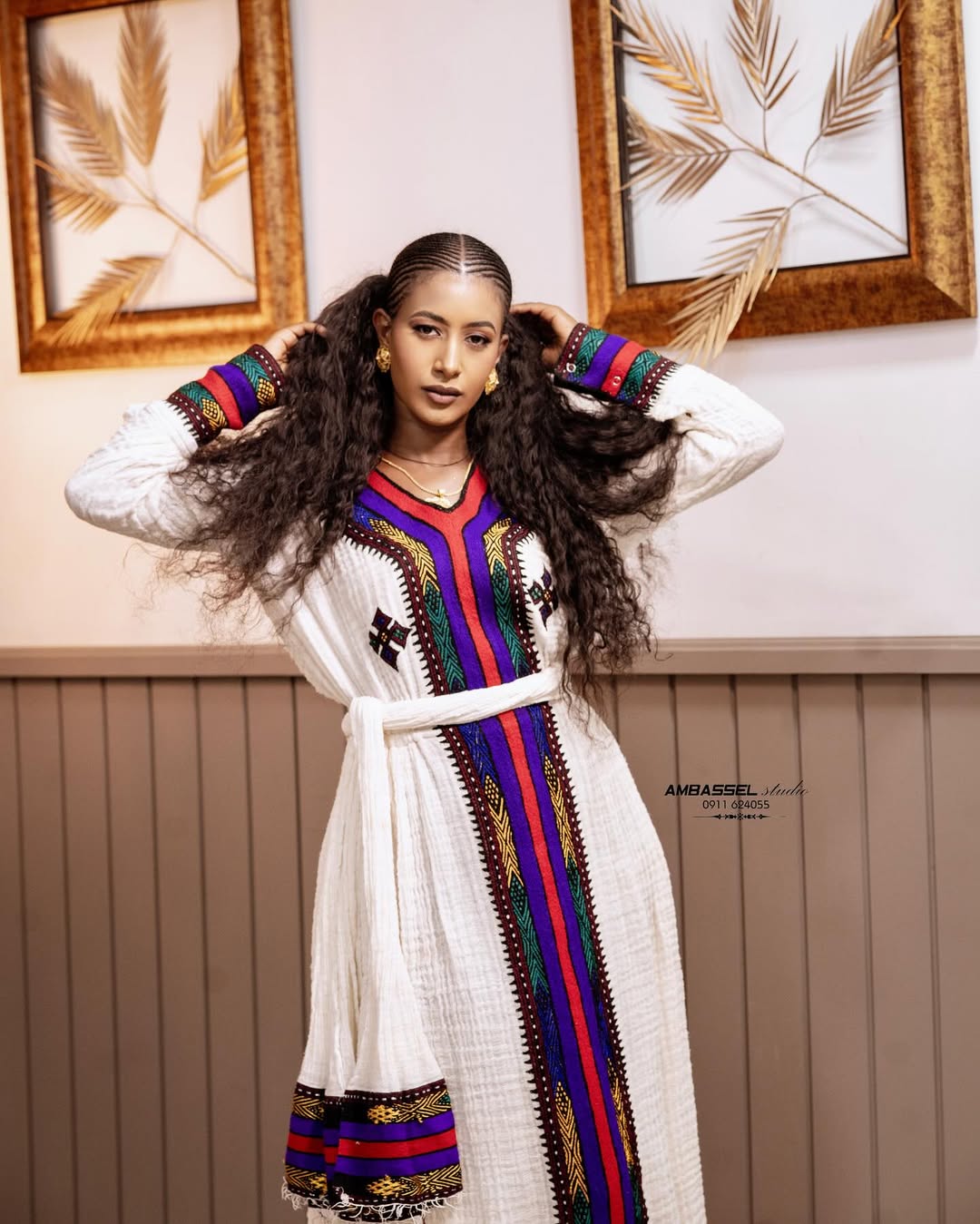 Woman in a traditional outfit with colorful patterns standing indoors. Elegant Ethiopian & Eritrean Axum Habesha Dress Ethgebya