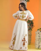 Woman wearing a white dress with gold and brown patterns against an orange background Golden Ethiopian Habesha Dress Handcrafted Zuria Kemis Set ethgebya gebeya usa zuria habesha kemis 