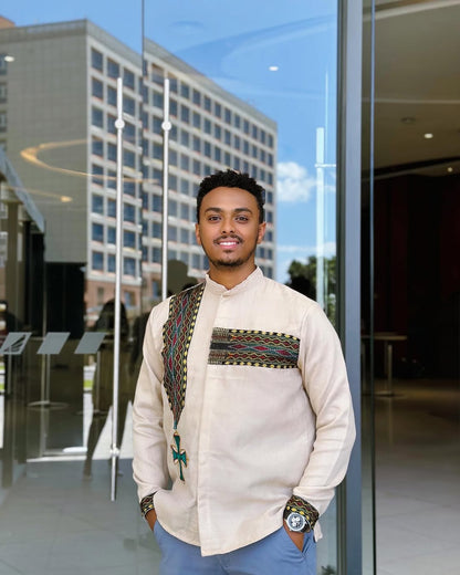 Man wearing a patterned shirt standing in front of a glass building. Cream Luxury Habesha Men’s Shirt New Modern Ethiopian Style ethgebya gebeya wen wond habehsa