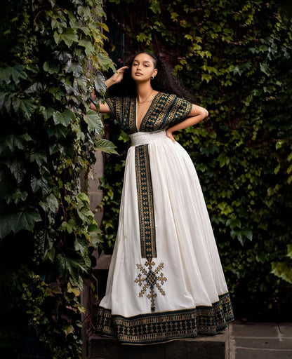 Woman wearing a traditional outfit with a white skirt and black top against a green leafy background. Golden & Green Modern Habesha Kemis Elegant Ethiopian ethgebya gebeyaDress
