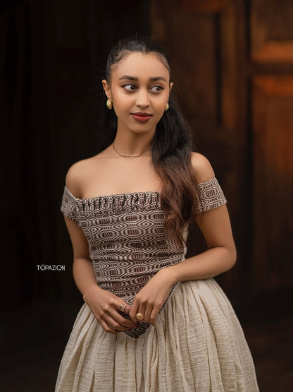 Woman wearing a patterned top and beige skirt against a dark background Modern Brown & Beige Habesha Kemis ethgebya