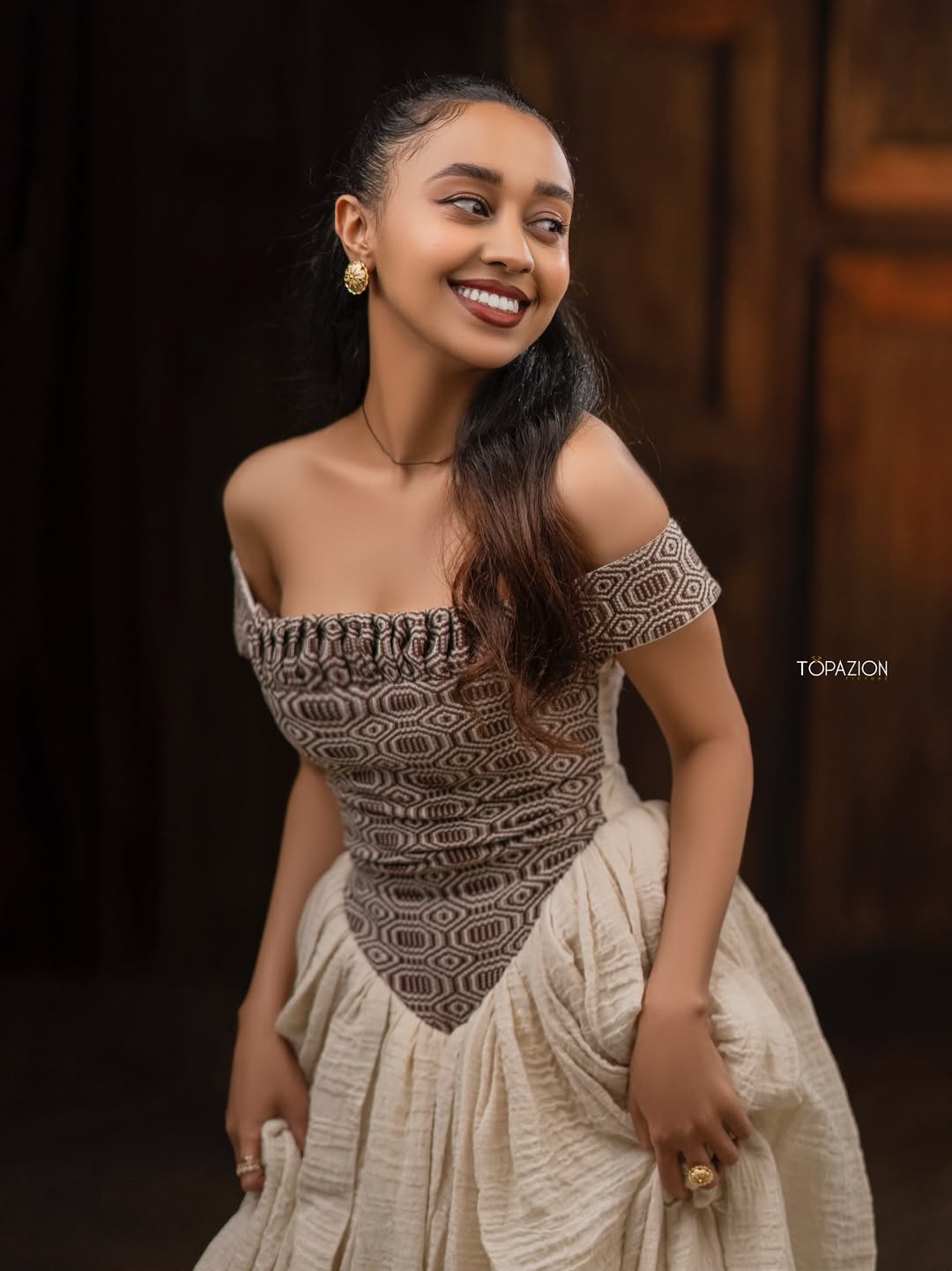 Woman wearing a patterned top and beige skirt with a blurred background Modern Brown & Beige Habesha Kemis ethgebya