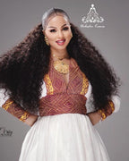 Woman with long, flowing hair wearing a traditional outfit with intricate patterns on a gray  background. Modern Zuria Habesha Kemis Handwoven Ethiopian & Eritrean Dress Ethiopian Gebeya Ethgebya