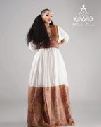 Woman wearing a traditional outfit with a white and brown dress on a gray background Modern Zuria Habesha Kemis Handwoven Ethiopian & Eritrean Dress Ethiopian Gebeya Ethgebya