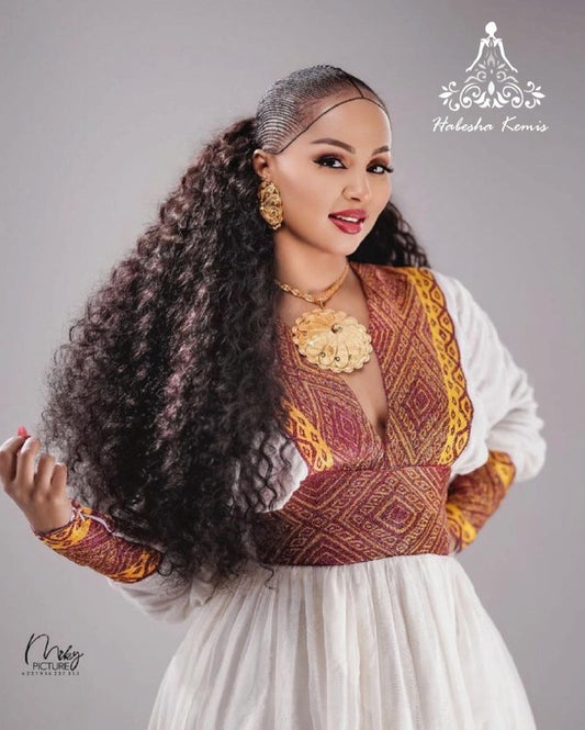 Woman in traditional attire with intricate patterns on a gray background. Modern Zuria Habesha Kemis Handwoven Ethiopian & Eritrean Dress Ethiopian Gebeya Ethgebya