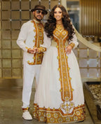 Man and woman in matching traditional outfits with gold and white patterns, standing indoors. Golden Ethiopian Habesha Couple Outfit | New Matching Modern Set
