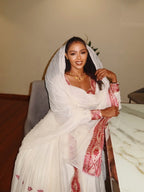 Woman wearing a white saree with red patterns, sitting indoors. New Pink Zuria Habesha Kemis Handcrafted Ethiopian Traditional Dress Ethiopia Gebebya Ethgebya