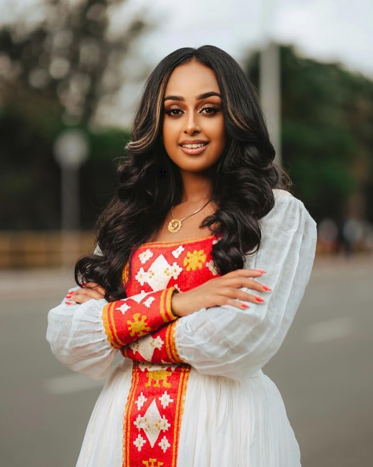 Woman wearing a traditional outfit with red and white patterns outdoors. Beautiful Red Zuria Habesha Kemis New Modern Ethiopian Dress ethgebya gebeya usa habesha kemis