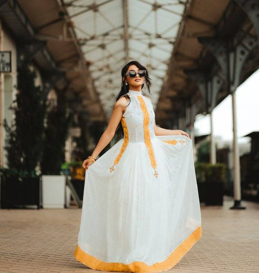 Woman in a white dress with yellow accents standing outdoors. Yellow Modern Zuria Habesha Kemis Handcrafted Ethiopian Dress ethgebya gebeya usa habesha kemis