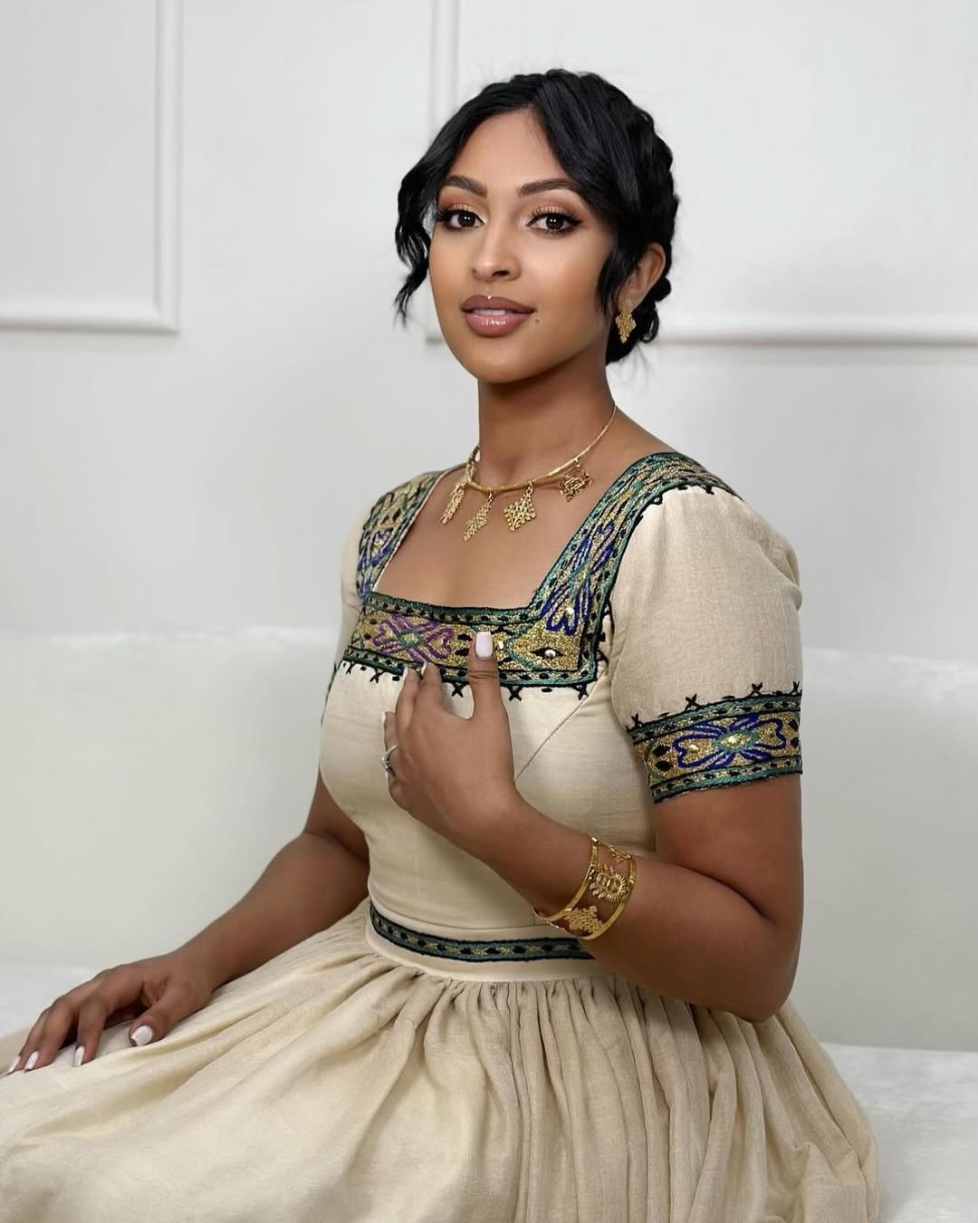 Woman wearing a traditional outfit with intricate designs on a white background. New Beige Zuria Habesha Kemis Modern Handcrafted Ethiopian Dress ethgebya gebeya