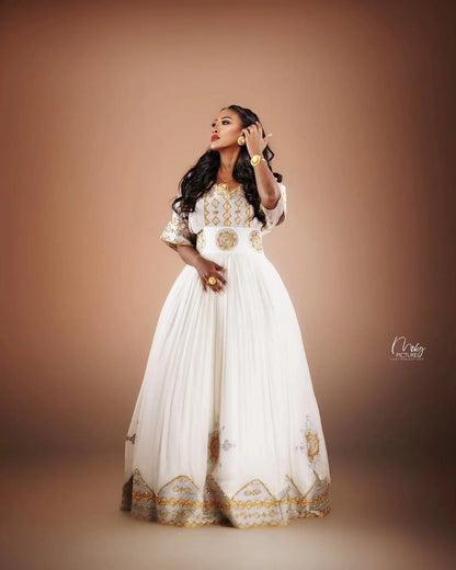 Woman in a white and gold dress against a brown background Golden Modern Zuria Habesha Kemis Elegant Ethiopian Traditional Dress ethgebya