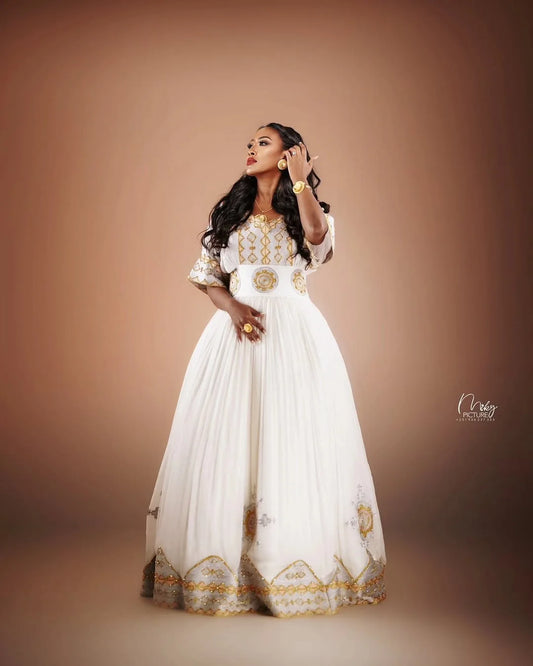Woman in a white and gold dress against a brown background Golden Modern Zuria Habesha Kemis Elegant Ethiopian Traditional Dress ethgebya