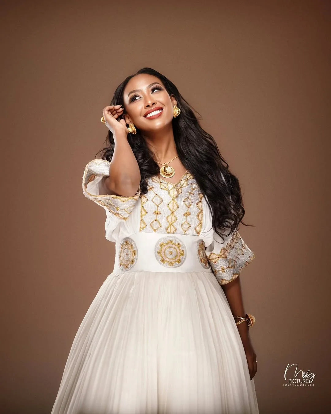 Woman in a white and gold dress posing against a brown background Golden Modern Zuria Habesha Kemis Elegant Ethiopian Traditional Dress ethgebya