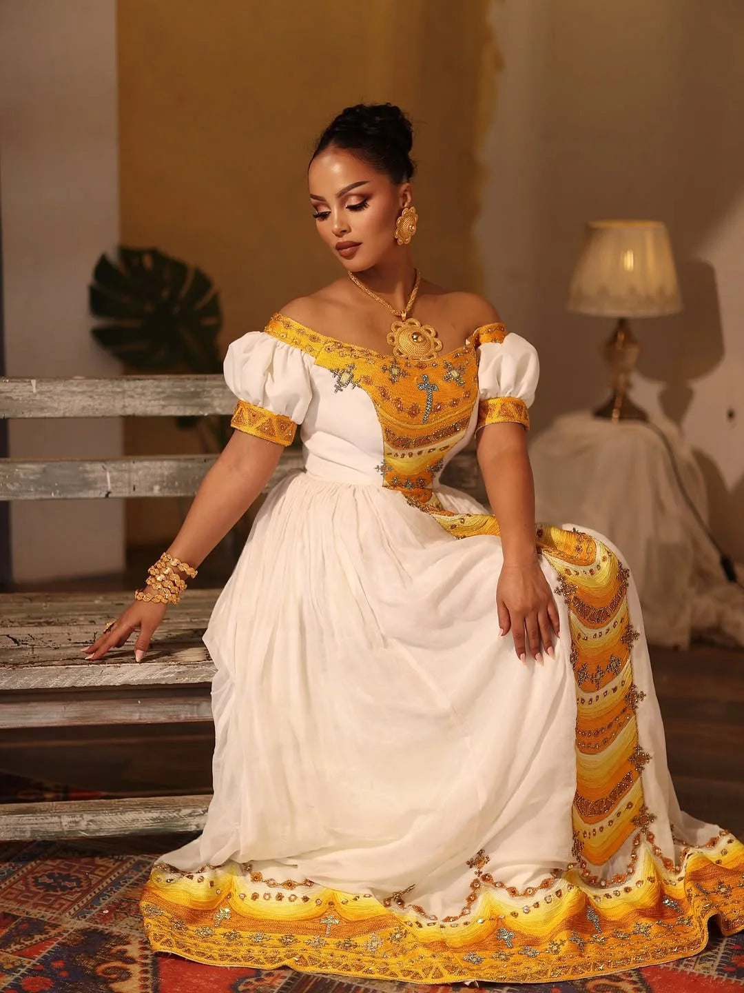 Woman in a white and yellow traditional outfit sitting on a wooden staircase. Yellow Modern Zuria Kemis Elegant Handcrafted Ethiopian Dress ethgebya gebeya