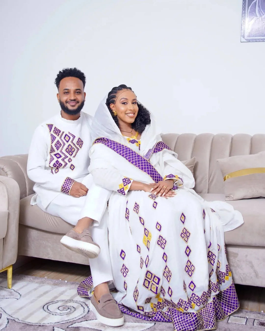 Couple in traditional attire sitting on a couch in a living room.  Purple Habesha Couple Outfit New Matching Ethiopian Traditional Set ethgebya gebeya